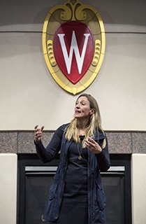 Stephanie Pugliese speaks underneath the UW crest.