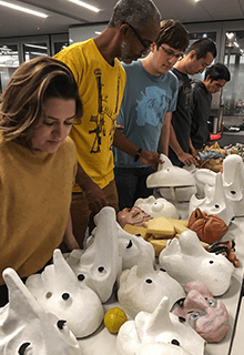 Students select from a row of masks in a class titled Performing Information.