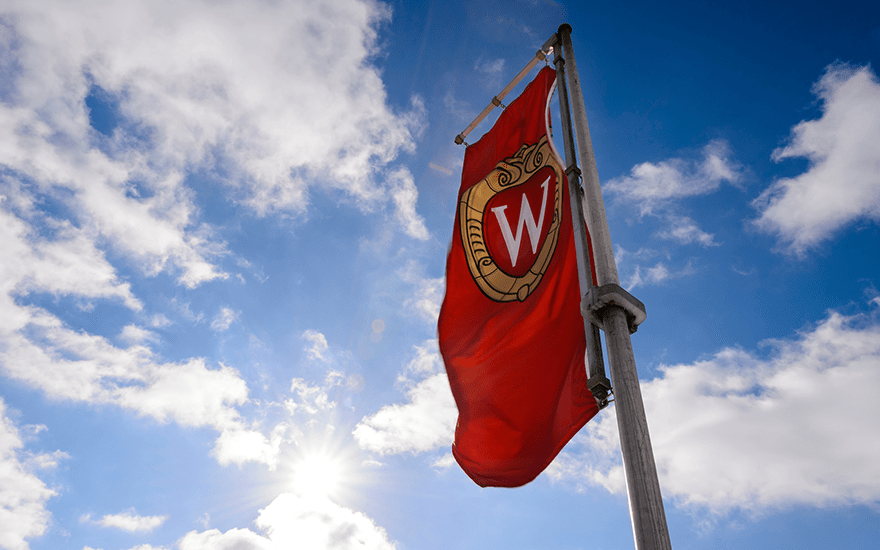 The UW-Madison crest appears on a flag waving in the wind.