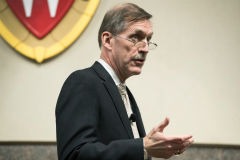 Karl F. Schneider stands in front of the Wisconsin crest as he speaks