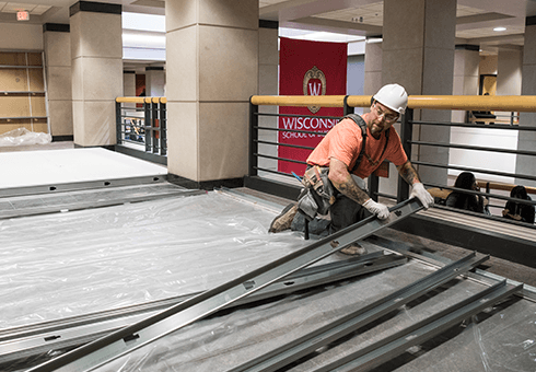 A construction worker lays building material inside Grainger Hall