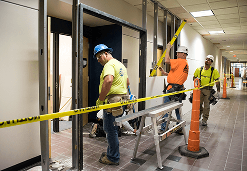 Three construction workers build temporary walls during the Learning Commons renovation