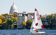 A UW-Madison sailboar slides across Lake Mendota on a warm summer day.