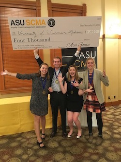 Four BBA students hold up giant check for Four Thousand dollars