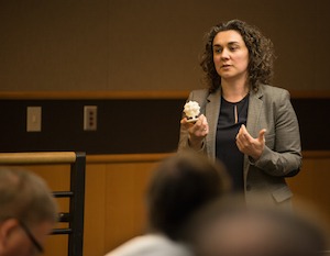 Natalie Rudolph holds 3D print object as she speaks to audience