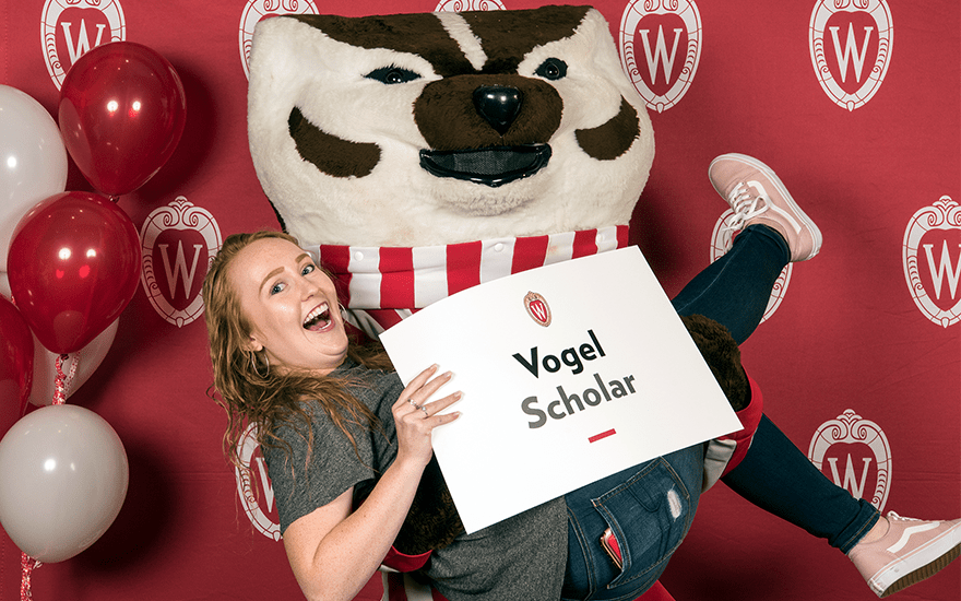 Bucky Badger holds a smiling female BBA student.