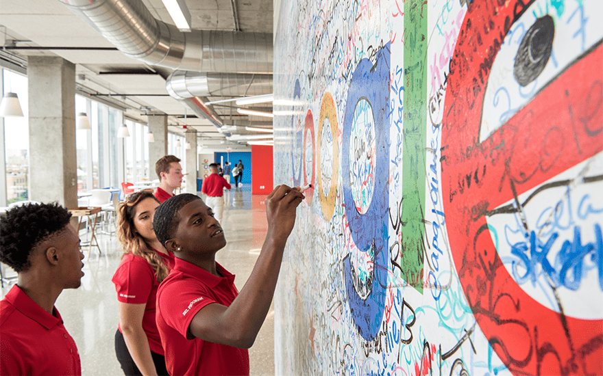 Students sign a wall with the Google logo at the company's office
