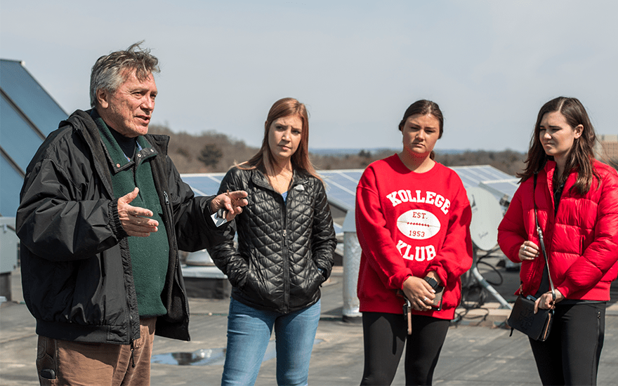 Tom Landgraf speaks to student on a rooftop with solar panels