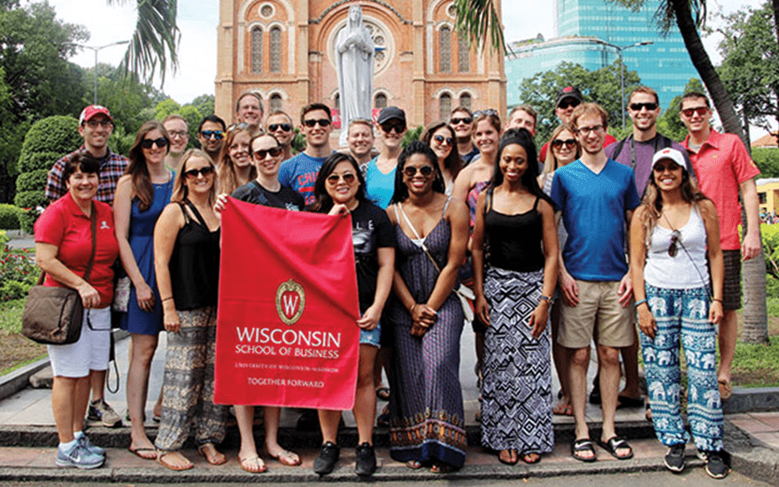 A group of MBA students hold a WSB flag in Vietnam