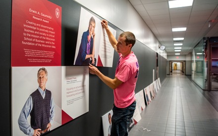 A man adding an image to the Gaumnitz Research Award Winners wall