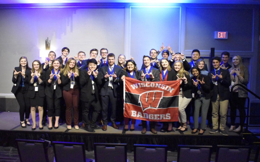 DECA regional competitors on stage holding UW-Madison flag