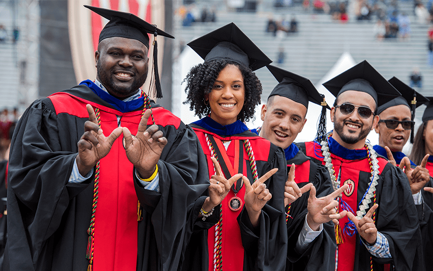 A group of Wisconsin MBA graduates proudly wear their cap and gowns.