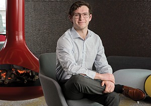 WSB graduate Max Fergus smiles at the office for his startup company