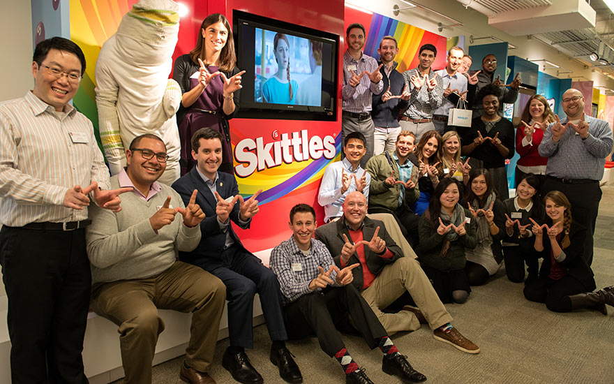 Students pose in front of a Skittles company display