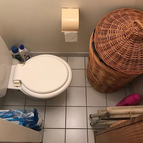 Host family toilet with clothes basket very close to the front of the toilet bowl