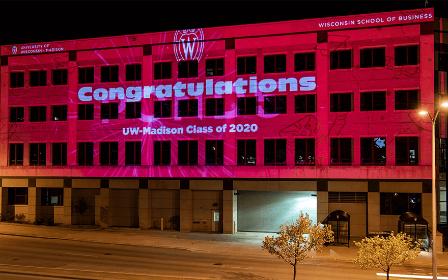 The exterior of Grainger Hall is illuminated with congratulatory messages for graduates