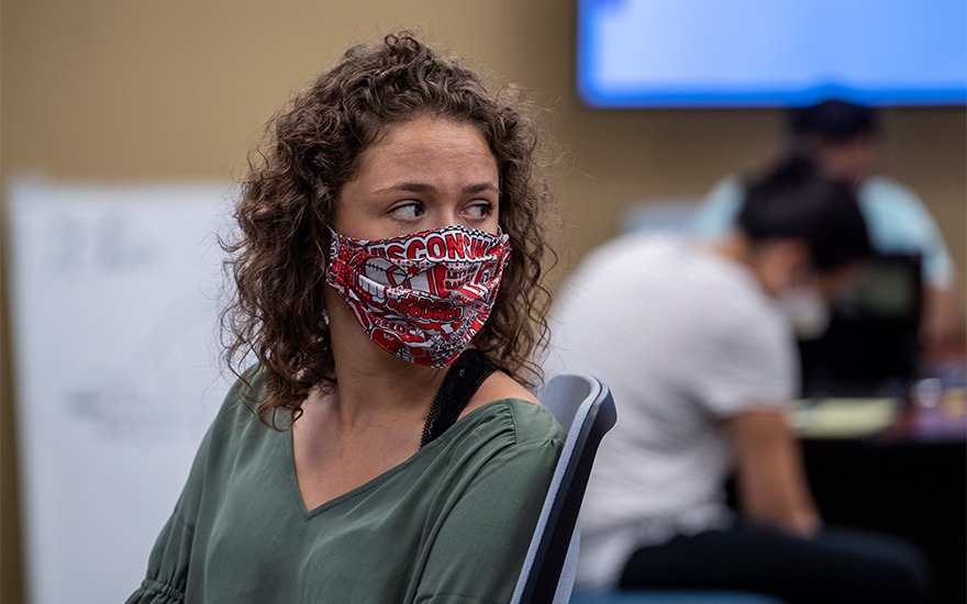 A female student wearing a University of Wisconsin face mask