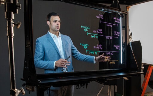 Professor Fabio Gaertner films an online class in front of a lightboard