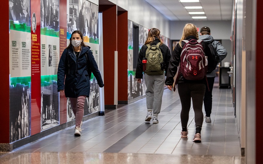 Students wearing masks walking past the Legacy Wall