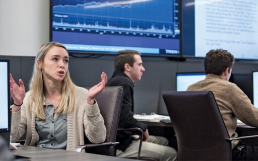 Student speaking in front of screen in finance and analytics lab