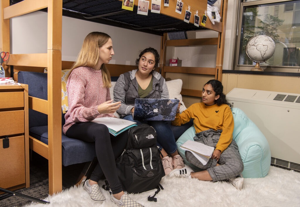 Three students work together in a dorm room