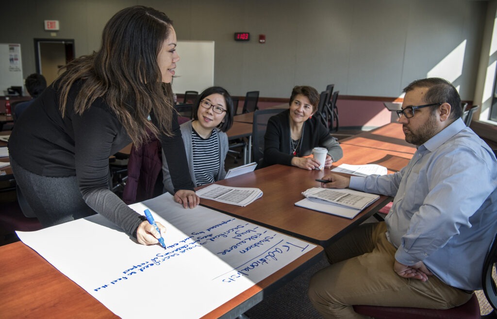 Four people collaborate on making a large poster