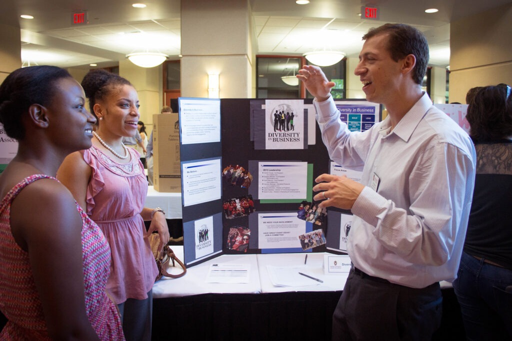 Two women talking with a man at the Student Organization Fair