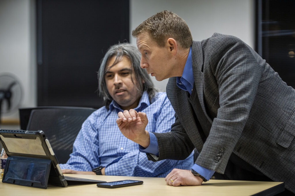 Two people working over laptop