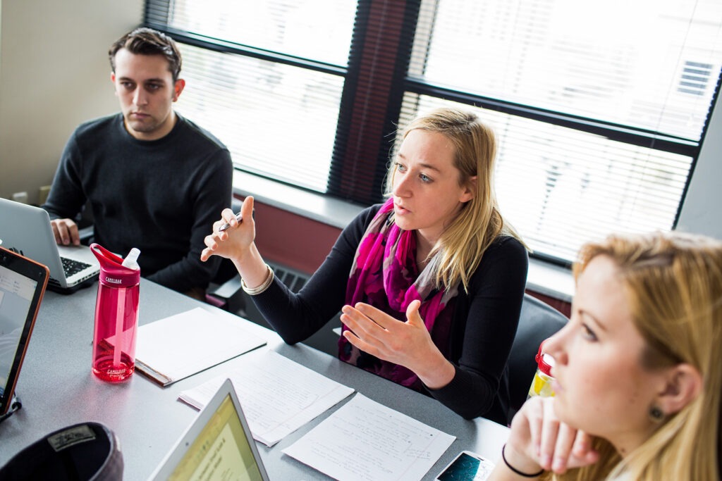 3 students talking over a table