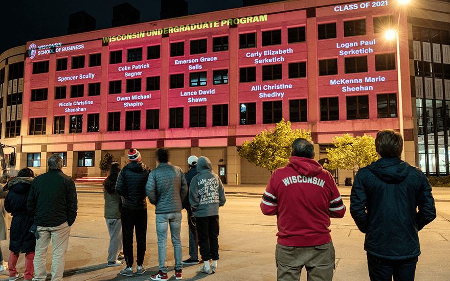 Grainger Hall with undergraduate graduates on the side of the building