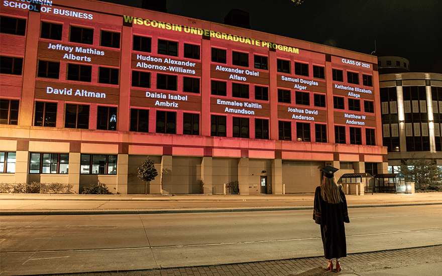 Grainger Hall with undergraduate graduates on the side of the building