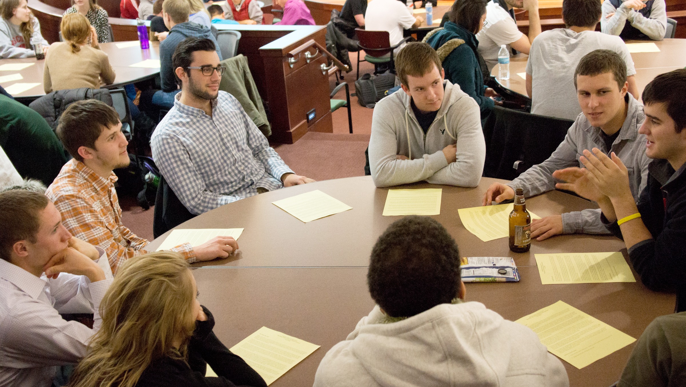 Nine people sitting at a round table talking