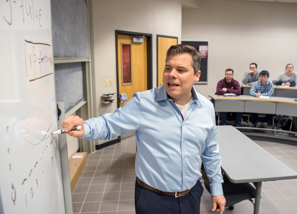 Instructor Dani Bauer writing on a whiteboard as he is teaching a class