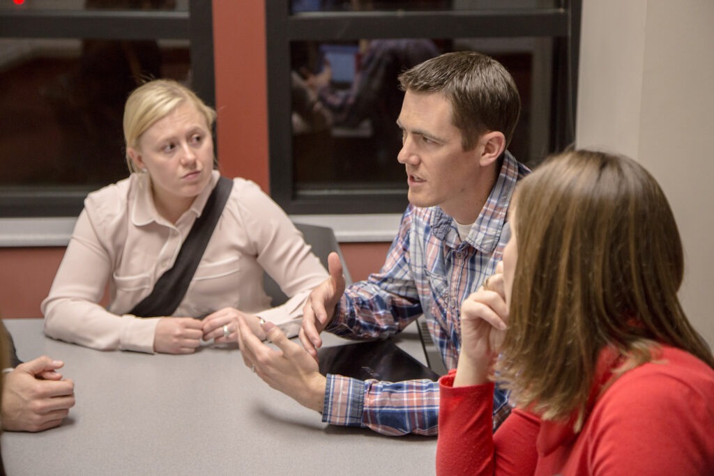 A man sitting at a table talking with a group of people