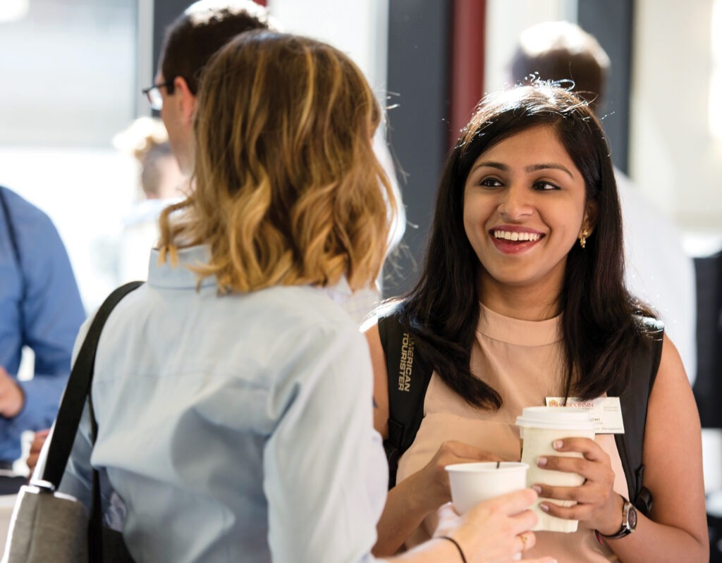 Two women standing and talking with drinks in their hands