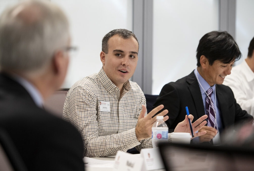 A man sitting with a group of people and talking with them.