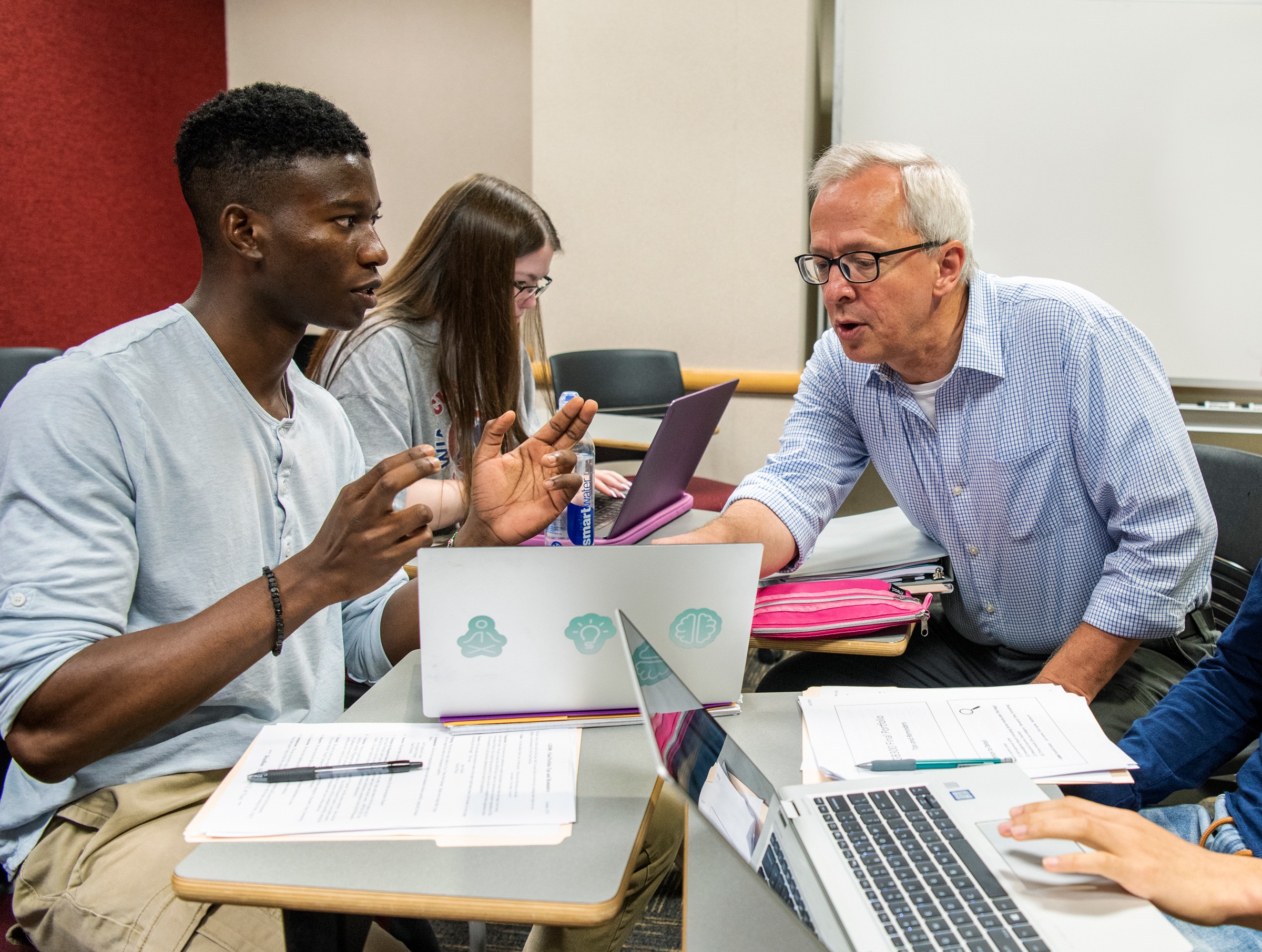 A student and a teacher sitting at a table talking over a laptop