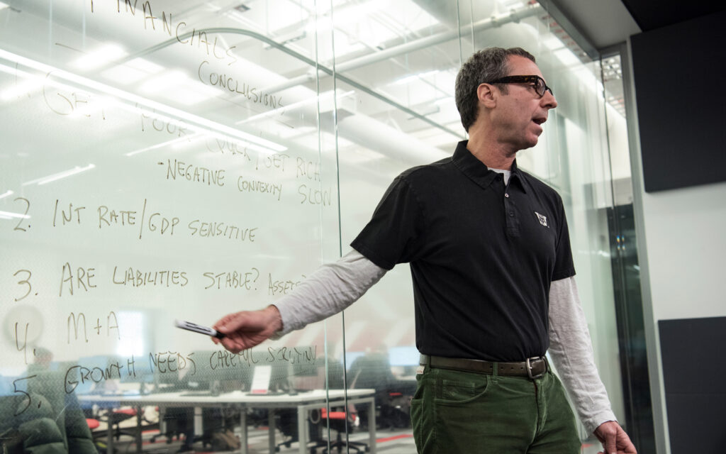 Professor pointing at writing on the board behind him