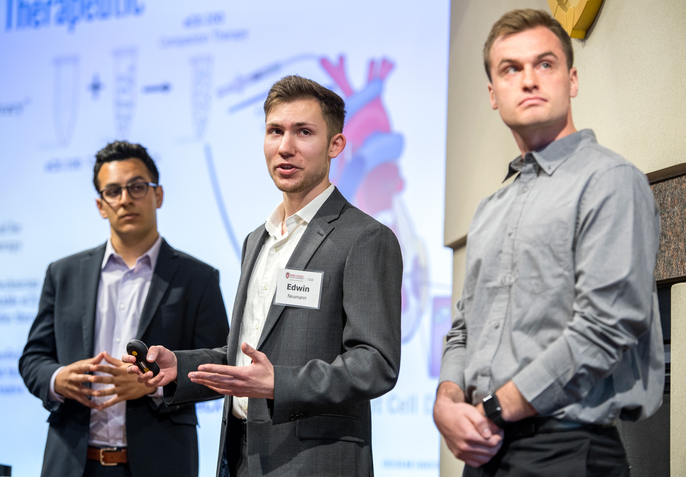 Three men giving a presentation on a stage