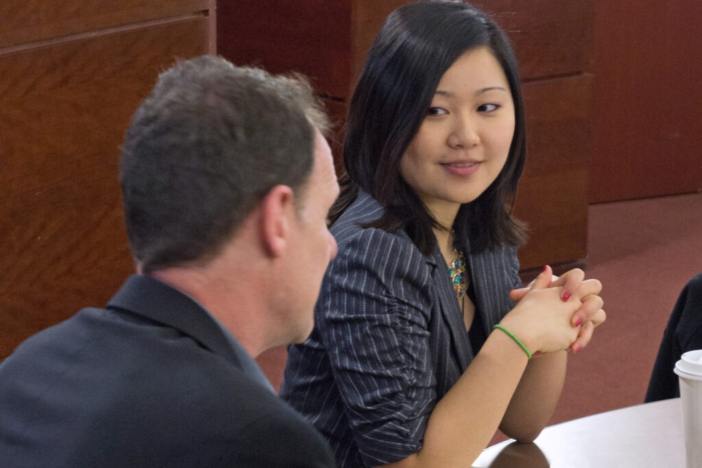 A woman smiling at a man while both are sitting at a table