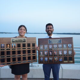 A man and a woman holding large plaques with headshots on the plaques