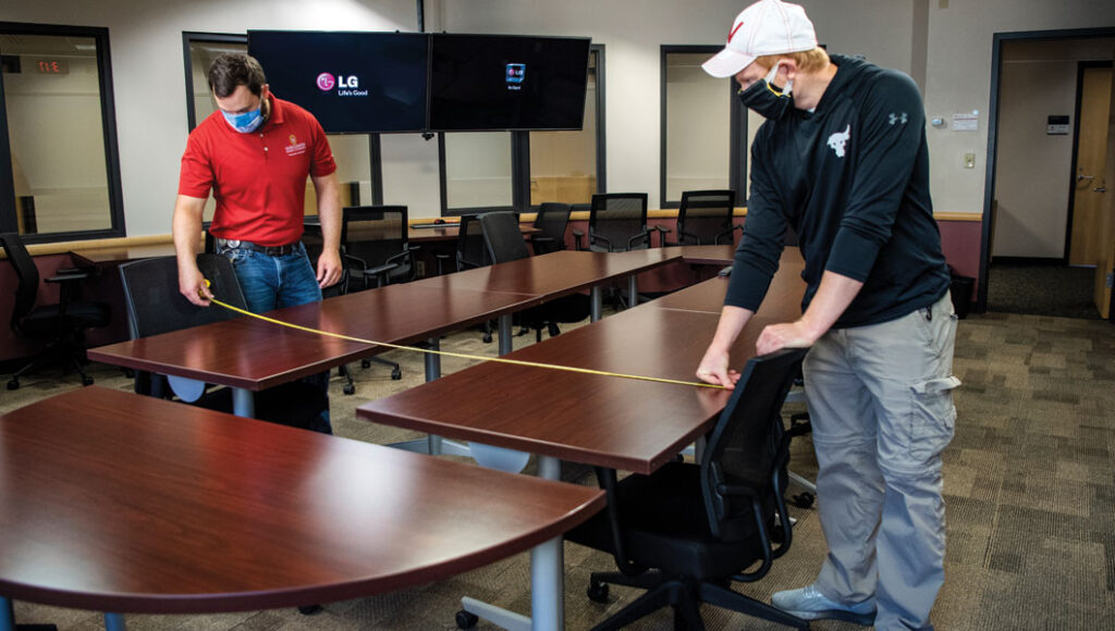 Tim Bent and Josh Crom reconfiguring furniture in Grainger Hall for social distancing.