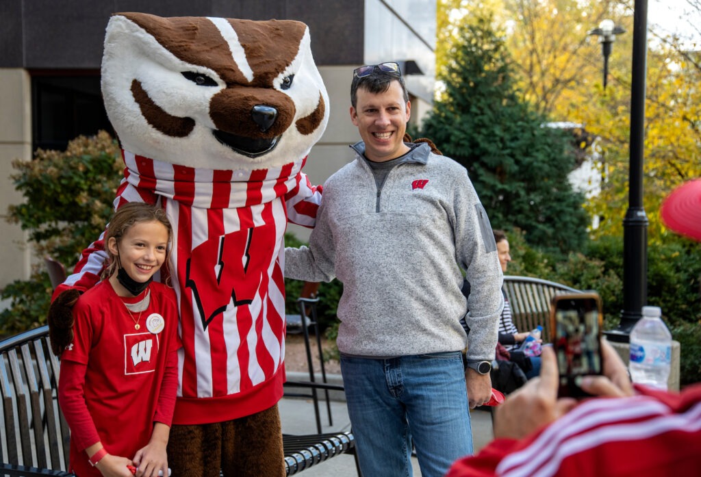 A man and a little girl with Bucky Badger