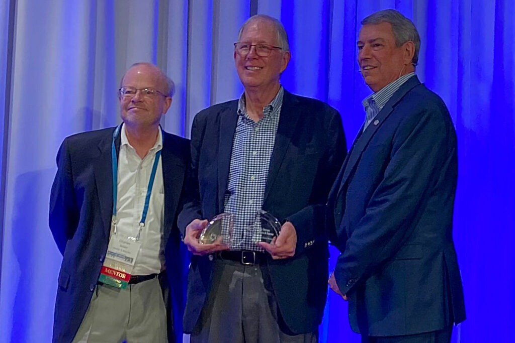 Joe Boucher stands onstage with award from the WI Technology Council