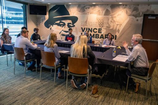 Students collaborate in a Lambeau field room decorated with Vince Lombardi's image and words