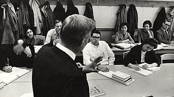 A teacher teaching a lesson with students taking notes at desks