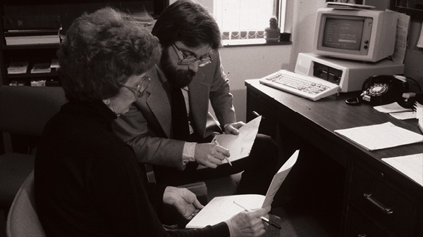 Two faculty members sitting with notes at a desk
