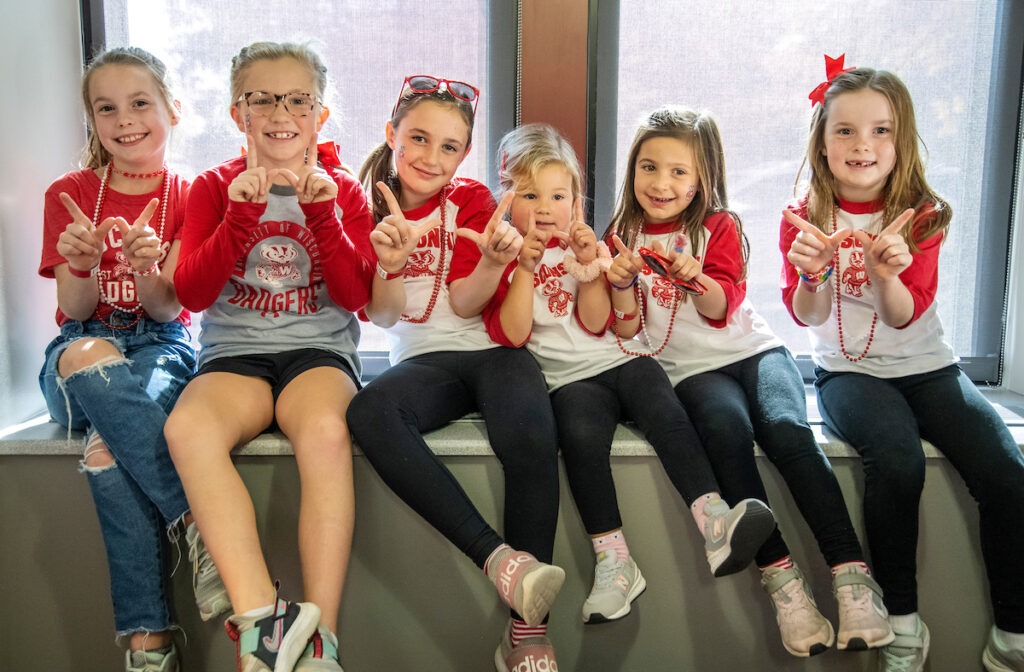 Children of alumni posing for a photo and displaying the 'W' sign.
