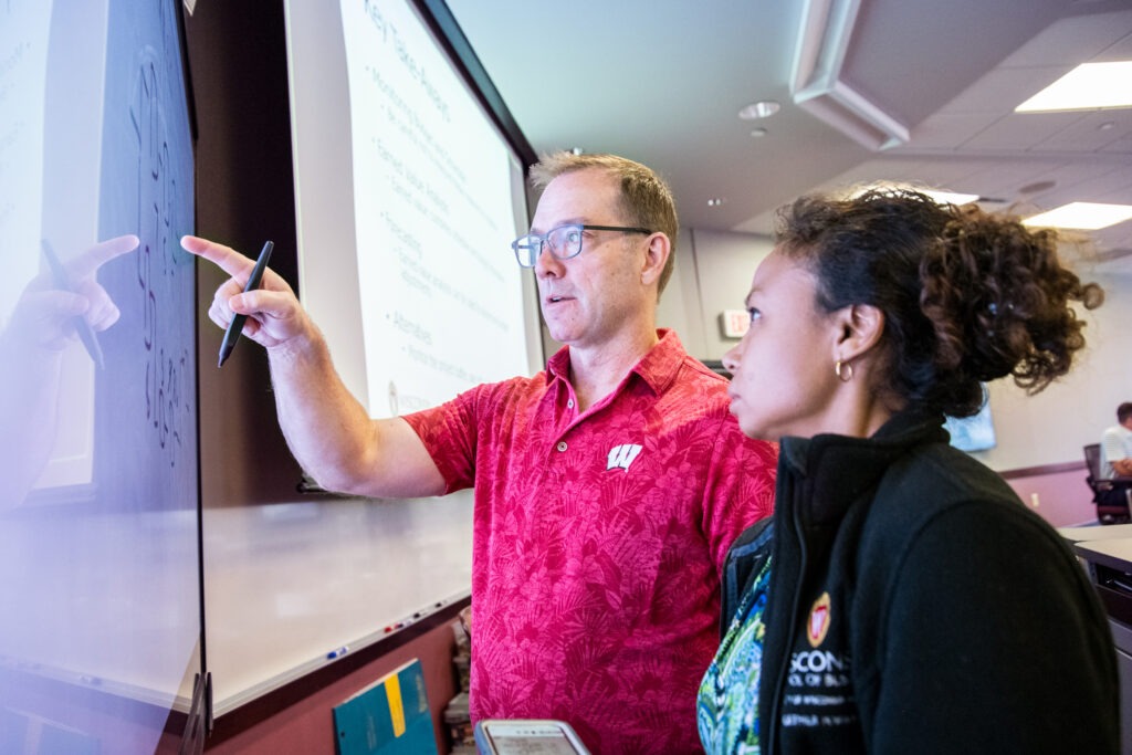 A man and a woman working at an interactive whiteboard