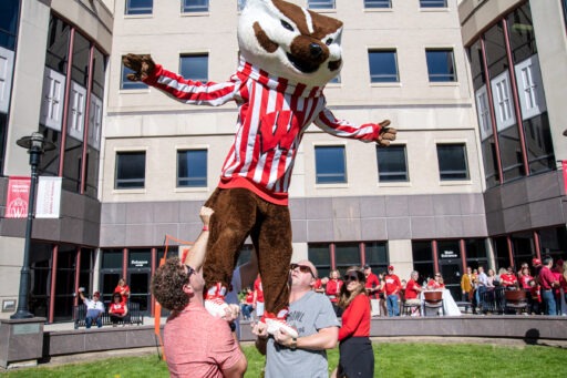 alumni lift up Bucky Badger in the Grainger Hall courtyard